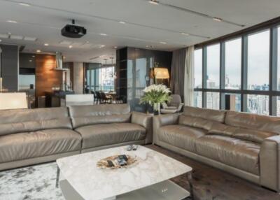 Modern living room with city view, leather sofas, and open kitchen