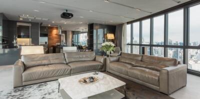 Modern living room with city view, leather sofas, and open kitchen