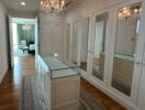 Elegant walk-in closet with glass top island and chandelier