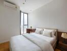 Modern bedroom with double bed, window, and air conditioning