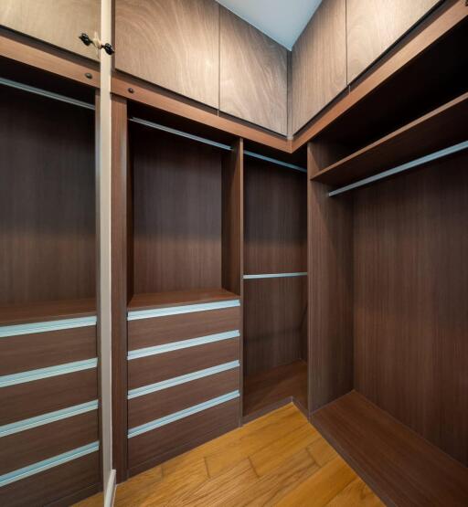 Spacious walk-in closet with wooden cabinetry and built-in shelves