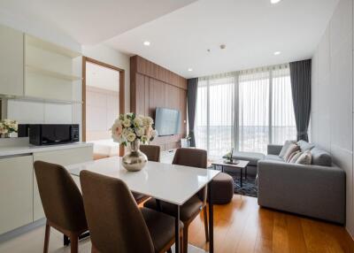 Modern living room with large windows, a dining table, and a gray sofa