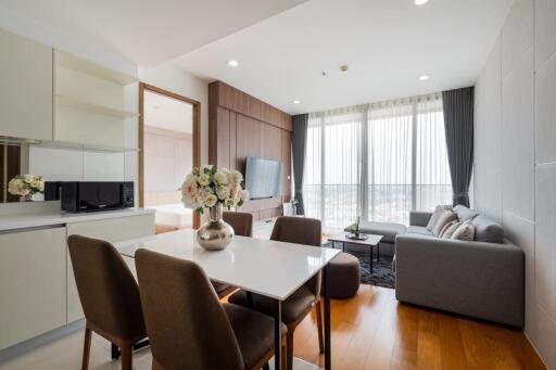 Modern living room with large windows, a dining table, and a gray sofa