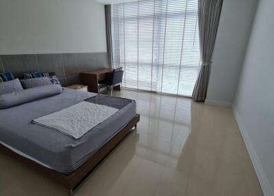 Modern bedroom with bed, desk, and large window with blinds