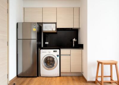 Modern kitchen with appliances including refrigerator, microwave, and washing machine