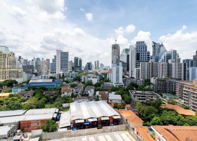 City skyline with various buildings and apartments under a partly cloudy sky.