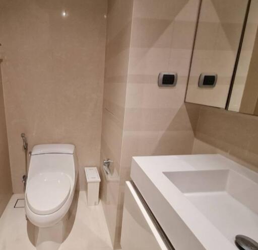 Modern bathroom with toilet, sink, and large mirror