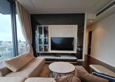 Modern living room with large windows, beige couches, a marble coffee table, and a TV