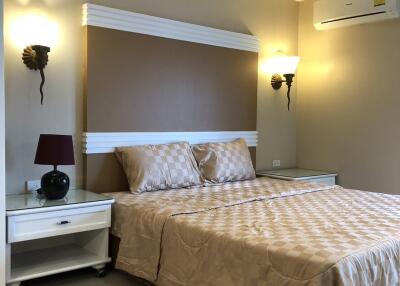 A neatly arranged bedroom with a double bed, two bedside tables, wall-mounted lights, and an air conditioner