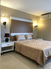 A neatly arranged bedroom with a double bed, two bedside tables, wall-mounted lights, and an air conditioner