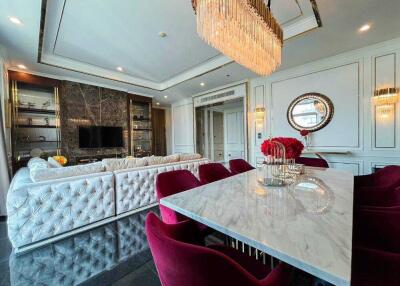 Spacious living room with dining area featuring a large sectional sofa, marble dining table, and elegant chandeliers