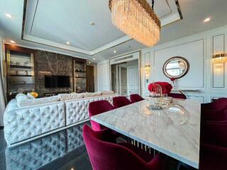 Spacious living room with dining area featuring a large sectional sofa, marble dining table, and elegant chandeliers