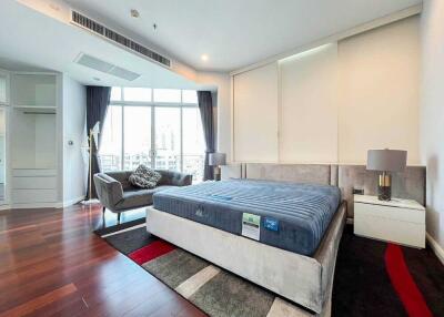 Modern bedroom with large bed, seating area, and city view