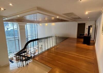 Spacious living area with wooden flooring and a modern glass railing overlooking a dining area