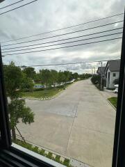 View outside from a window showing a street with houses and trees