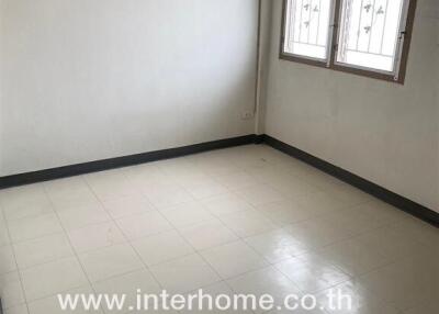 Small empty bedroom with tiled floor and barred windows