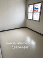 Small empty bedroom with tiled floor and barred windows