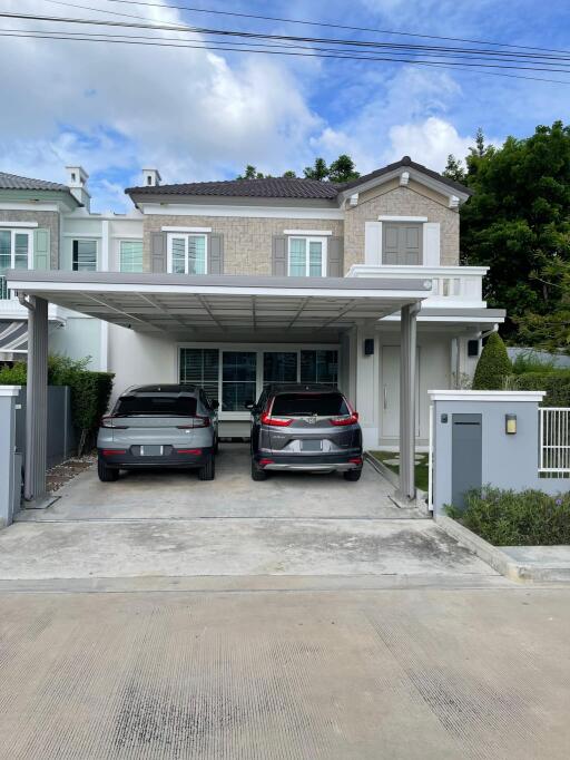 Two-story house with carport and two cars