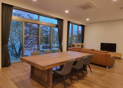 Spacious living room with large windows, wooden floor, and modern furniture