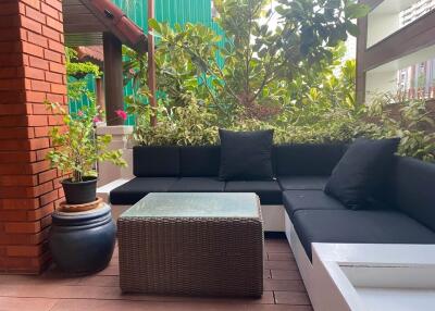 Outdoor seating area with black cushions and greenery