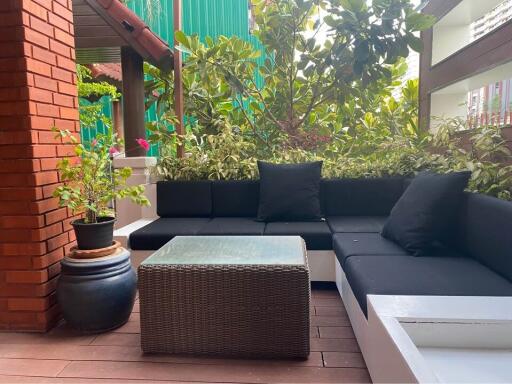 Outdoor seating area with black cushions and greenery