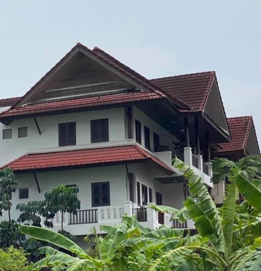 Exterior view of a multi-story building with red tiled roof and balconies