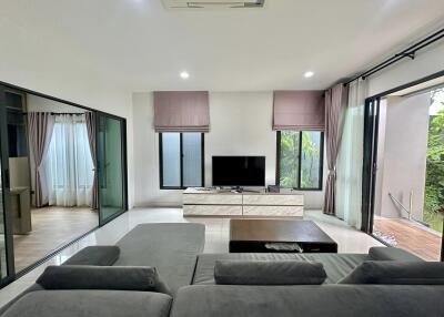 Modern living room with large windows, couch, and TV