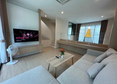 Modern living room with couch, TV, and large windows