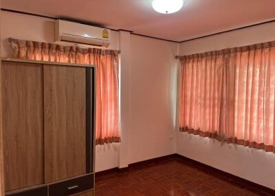 Bedroom with wooden wardrobe, air conditioner, and curtains