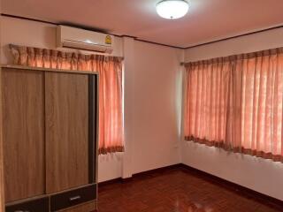 Bedroom with wooden wardrobe, air conditioner, and curtains