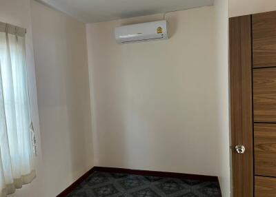 Small empty bedroom with air conditioner and a large wooden closet