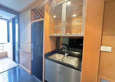 Compact kitchen area with glass cabinets, sink, and adjacent balcony.