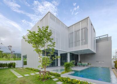 Exterior view of a modern house with a swimming pool and garden