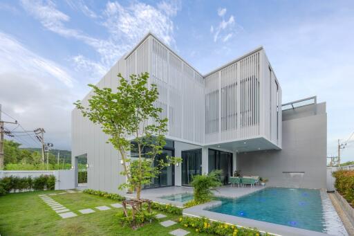 Exterior view of a modern house with a swimming pool and garden