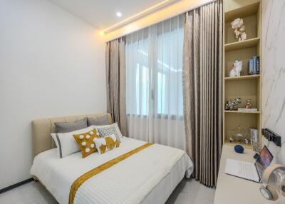 Cozy bedroom with a bed, decorative pillows, shelves, and a laptop on a desk