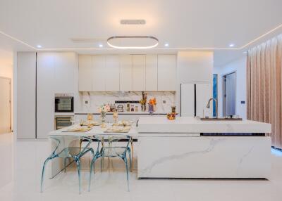 Modern kitchen with white cabinetry, marble island, and glass dining set