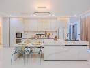 Modern kitchen with white cabinetry, marble island, and glass dining set