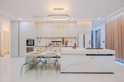 Modern kitchen with white cabinetry, marble island, and glass dining set