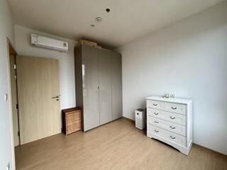 a bedroom with a wardrobe, air conditioning unit, a chest of drawers, a wicker basket, and a wooden door