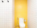 Modern bathroom with yellow tile wall and white toilet