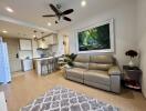 Modern living room with leather sofa, kitchen area, and hanging ceiling fan