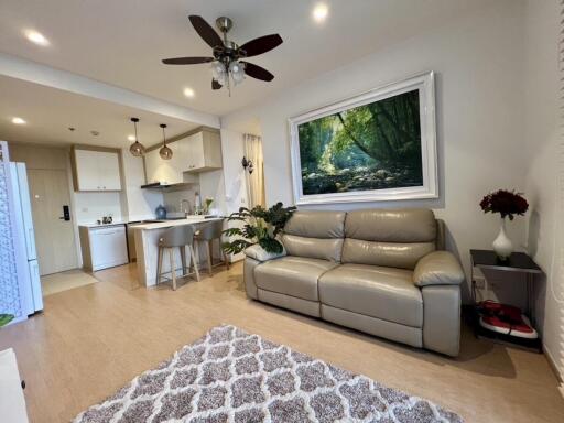 Modern living room with leather sofa, kitchen area, and hanging ceiling fan