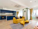 Modern open concept living and kitchen area with yellow sofa and blue cabinetry