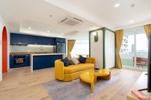 Modern open concept living and kitchen area with yellow sofa and blue cabinetry