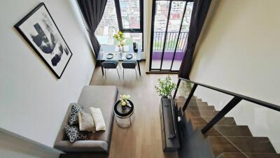 Modern living room with stairs and dining table near window