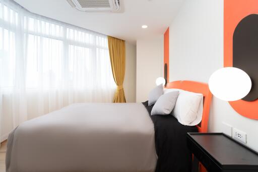 Modern bedroom with a bed, side table, and large window with yellow curtains