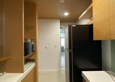 Modern kitchen with wooden cabinets, black refrigerator, and built-in microwave