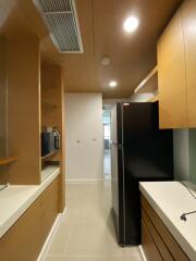 Modern kitchen with wooden cabinets, black refrigerator, and built-in microwave