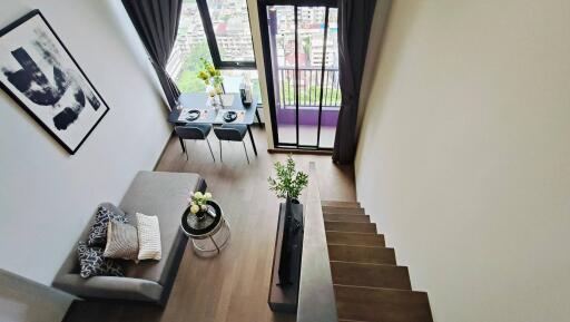 Modern living area with loft-style staircase and large window with city view