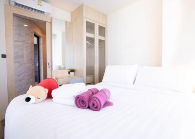 Bright and cozy bedroom with neatly arranged linens and a plush toy